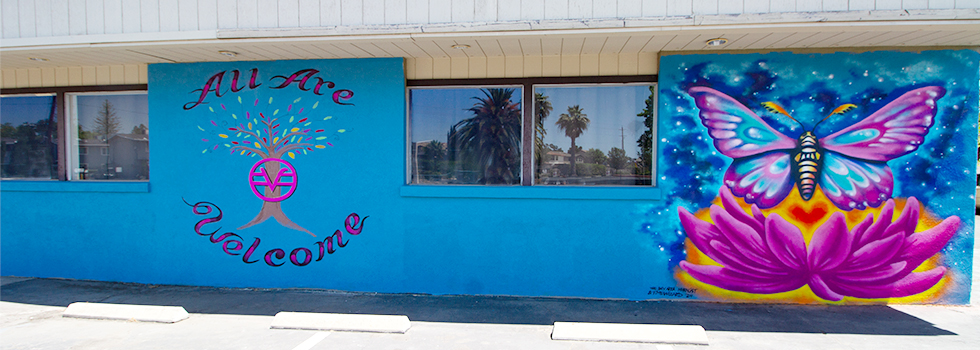 The All Are Welcome mural on the side of the center — a tree, a butterfly and a lotus